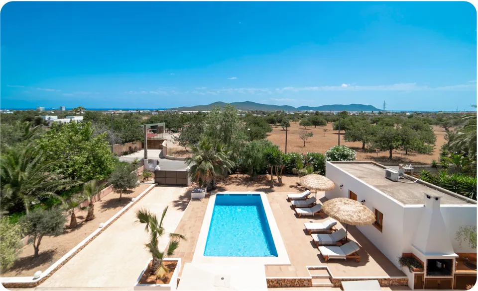 Ibiza-villa met zwembad, ligbedden en parasols, met uitzicht over amandelgaarden richting zee