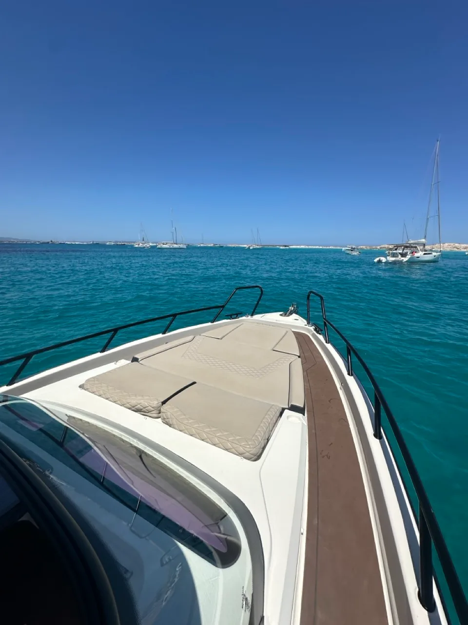 View over the bow of the NAVAN S30 across the turquoise anchorage off Formentera