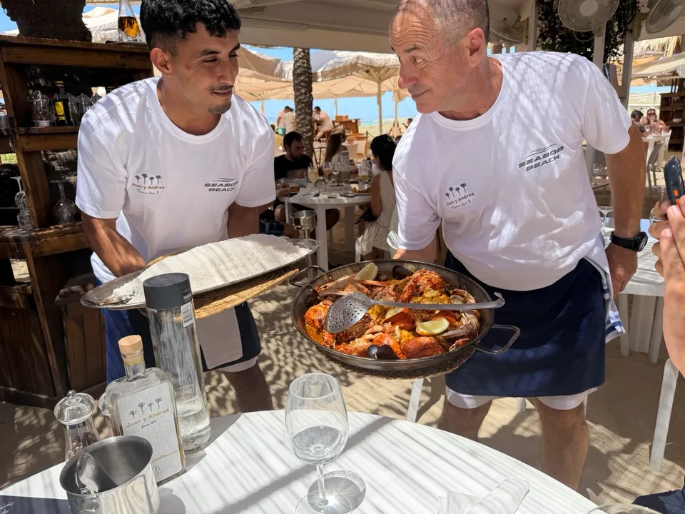 Waiters at Juan y Andrea on Formentera serving seafood paella and salt-baked fish beside the beach