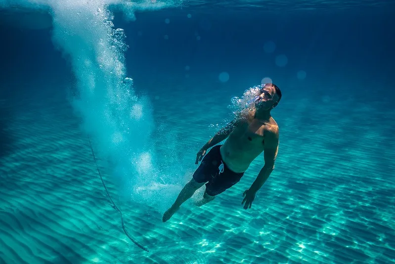 Snorkelaar glijdt net onder het wateroppervlak door helder turquoise water boven een zandbodem