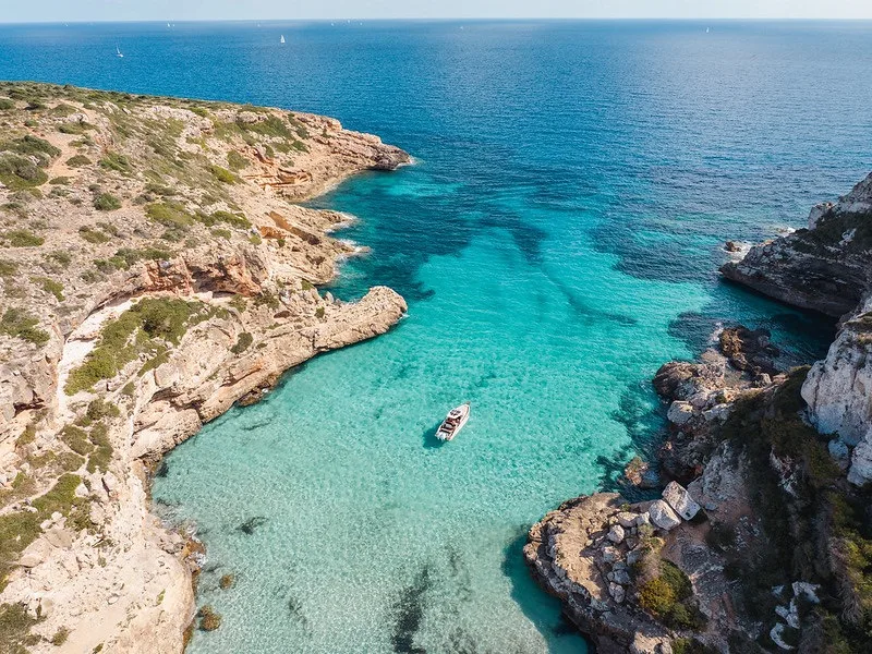 Boot ligt helemaal alleen voor anker in een afgelegen turquoise baai aan de kust van Ibiza