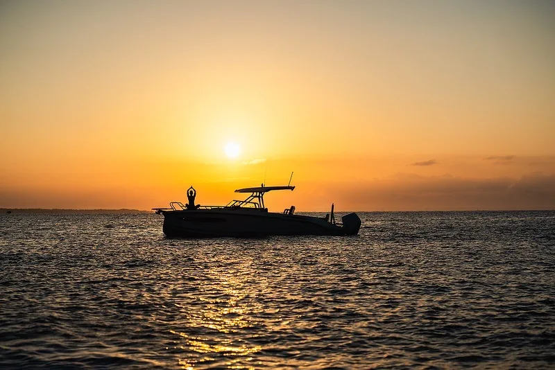 Silhouet van de NAVAN S30 voor anker bij zonsondergang met een gast op de boeg
