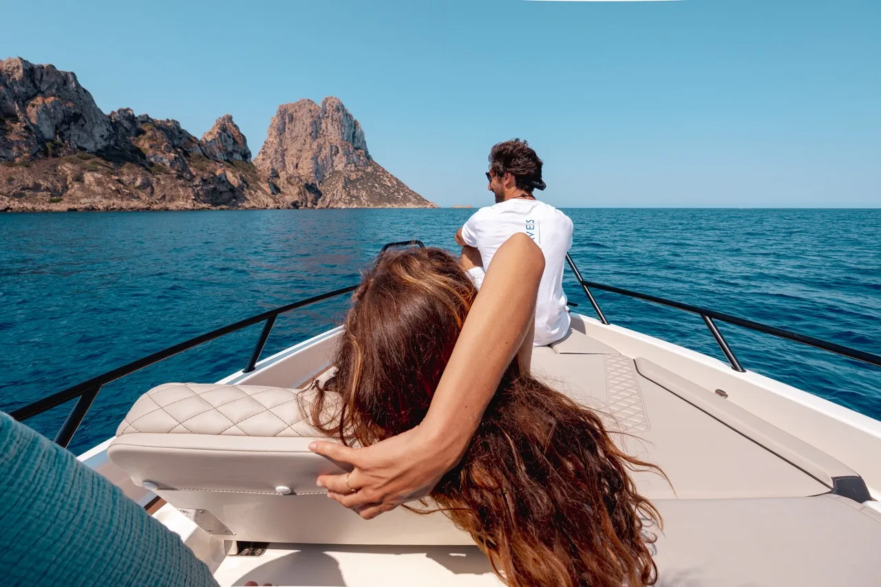 Two guests relaxing on the bow of the NAVAN S30 as the boat approaches the Es Vedrà rock