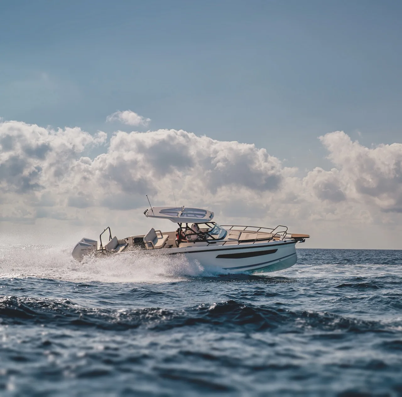 Skipper at the helm of the NAVAN S30 crossing open water under a dramatic cloudy sky