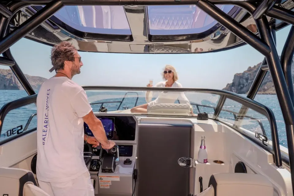 Professional skipper at the helm of the NAVAN S30 while a guest enjoys a drink on deck